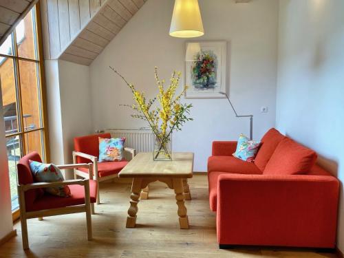 a living room with two red chairs and a table at Landhaus Sonneck in Weissensee