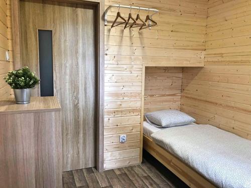 małą sypialnię z łóżkiem w drewnianym pokoju w obiekcie Świerkowy domek w Boszkowie