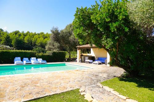 a swimming pool in a yard with chairs and a tree at Luxueux Mas provencal immérgé dans la nature in Le Castellet