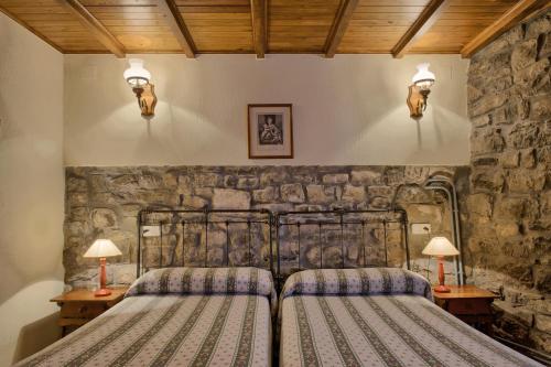 two beds in a room with stone walls at Casas Rurales El Llugarón in Miravalles