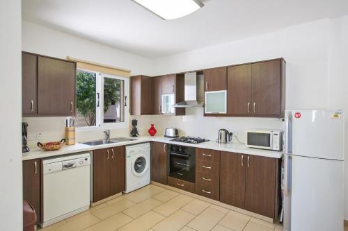 a kitchen with wooden cabinets and a white refrigerator at Protaras View Villa 5 in Protaras