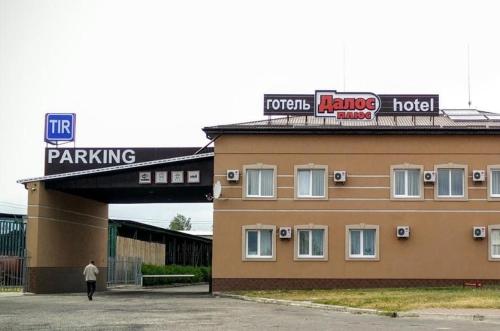 a man walking past a building with a parking lot at Dalos Plus in Sarny