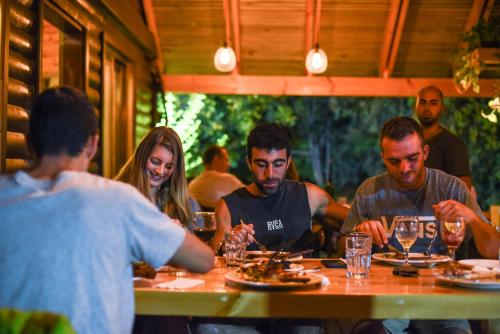 a group of people sitting at a table eating food at Cabin Resort in Moshav Ramot