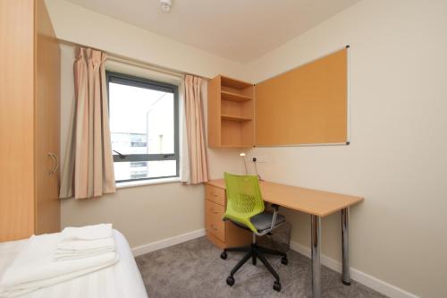 a bedroom with a desk and a green chair at Victoria Lodge Apartments - UCC Summer Beds in Cork
