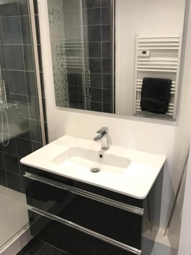 une salle de bain avec un lavabo blanc et un miroir dans l'établissement LE CLIO CARRÉ D'OR BEACH APARTMENT, à Nice