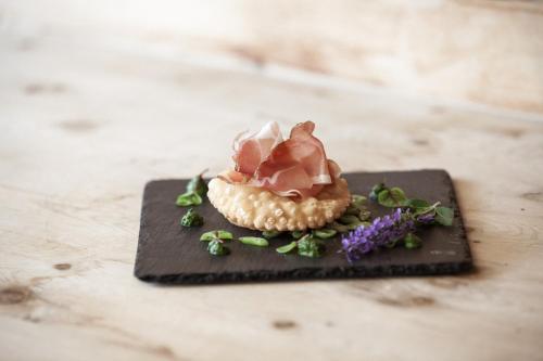 a small dessert on a black plate with flowers at Naturhotel Leitlhof in San Candido