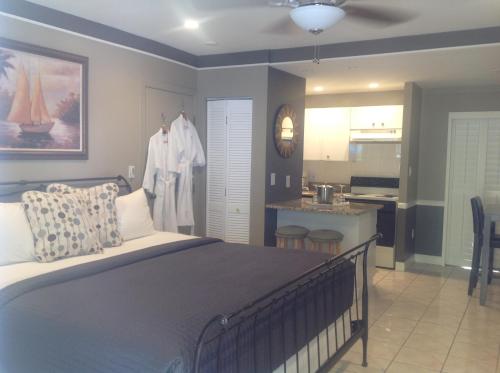 a bedroom with a large bed and a kitchen at Coral Reef Guesthouse in Fort Lauderdale
