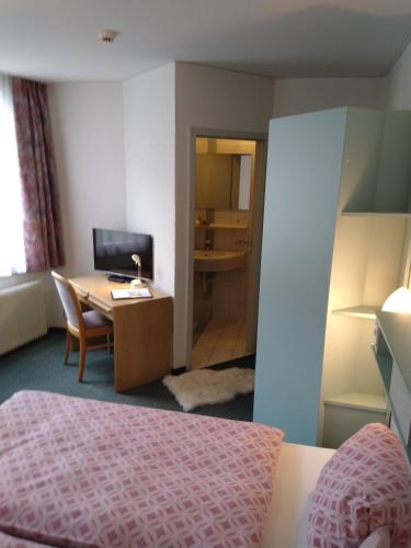 a hotel room with a desk and a bed and a table at Hotel Restaurant Escher in Leukerbad