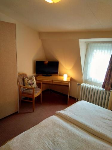 a bedroom with a bed and a desk with a television at Hotel Escher in Leukerbad