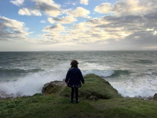 a woman standing on a rock looking at the ocean at Maison Glaz in Gâvres