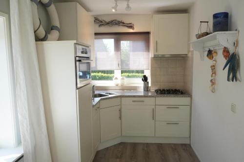 a kitchen with white cabinets and a sink and a window at Vakantiehuis Grevelingen 12 aan Grevelingenmeer. nabij Port Greve in Brouwershaven