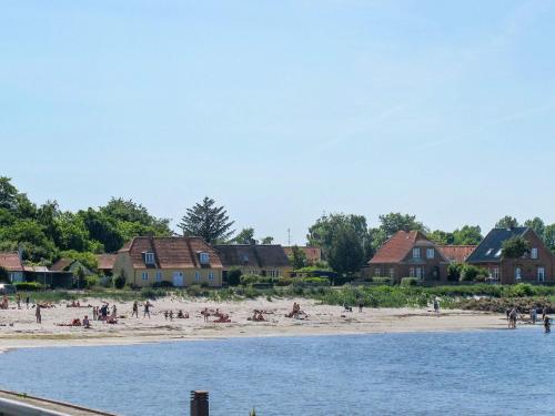 a group of people on a beach with houses at 4 person holiday home in Bandholm in Bandholm