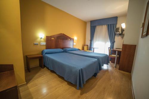 a bedroom with a bed with a blue bedspread at Hotel las Cruces in Belmonte de Miranda