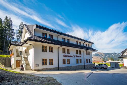 a white building with a car parked in front of it at Apartmany Biela Put - Veverica in Belá