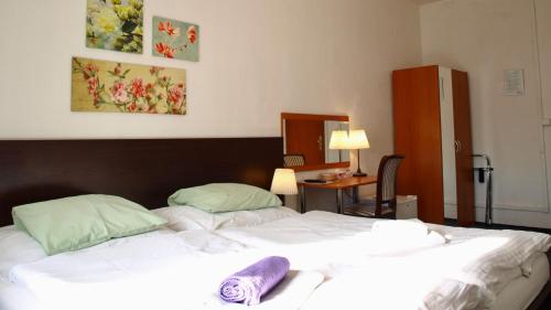 a bedroom with a large bed with white sheets and green pillows at Pension Village in Karlovy Vary