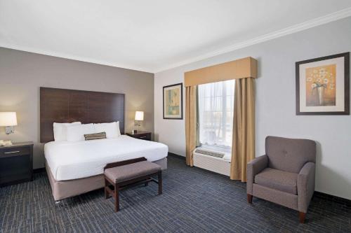 une chambre d'hôtel avec un lit et une chaise dans l'établissement Sonesta Essential Houston Westchase, à Houston