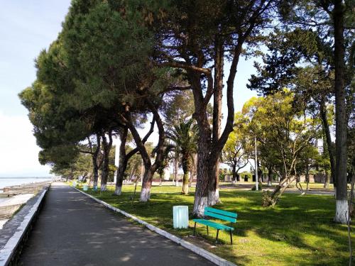 a park with a green park bench and trees at Чёрное Море in Ochamchira