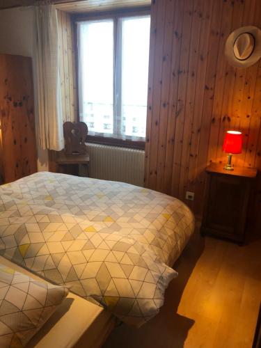 a bedroom with a bed and a lamp and a window at Au village d'Evolène, bel appartement avec terrasse in Evolène