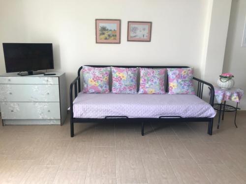 a room with a bed with pillows and a tv at Armonia Apartment in Plataria