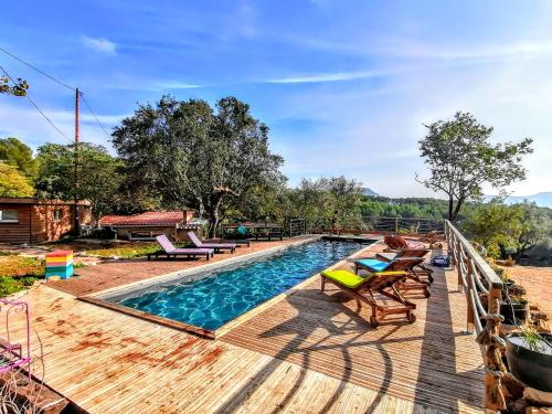 einen Pool mit Liegestühlen auf einer Holzterrasse in der Unterkunft Arche de Noé atypique, bohème , nature, piscine chauffée toute l'année, spa , sauna , loisirs in Le Beausset