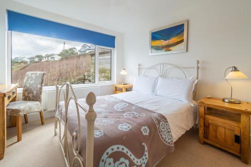 a bedroom with a bed and a desk and a window at Adanac in Sennen Cove
