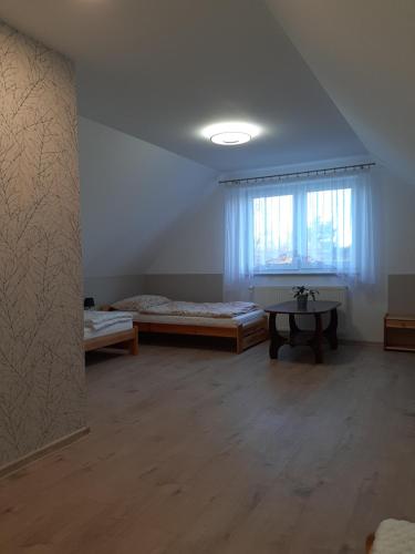 Una habitación con dos camas y una mesa y una ventana. en Dom Wakacyjny na Wsi Blisko Morza, en Kukinia