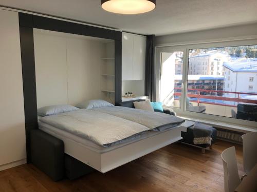 ein Schlafzimmer mit einem großen Bett und einem großen Fenster in der Unterkunft Ferienwohnung 405 Haus Allod in Lenzerheide