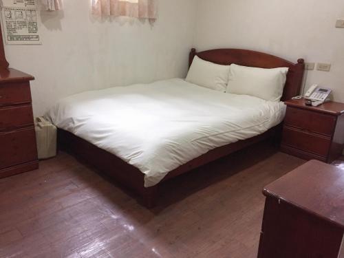 a bedroom with a bed with white sheets and a telephone at Xiang Dou Hotel in Jiaoxi