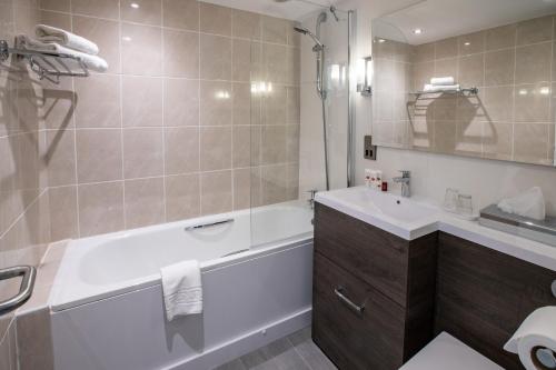 a bathroom with a bath tub and a sink at Park Hall Hotel and Spa Wolverhampton in Wolverhampton
