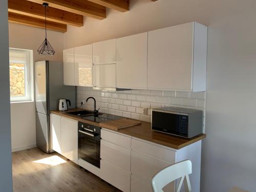 a kitchen with white cabinets and a microwave at Wakacyjny Hartowiec 2 in Grodziczno