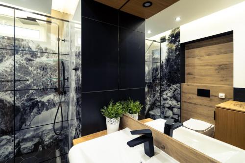 een badkamer met zwarte muren, een wastafel en een bad bij CHARDONNAY APARTMENT ZAKOPANE Centrum Jagiellońska Residence in Zakopane