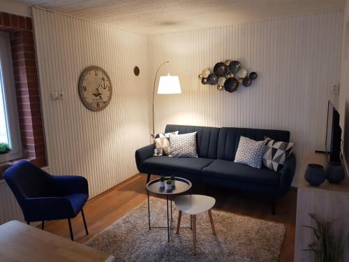 un soggiorno con divano, tavolo e orologio. di Het Huisje Klein maar Fijn a Bár