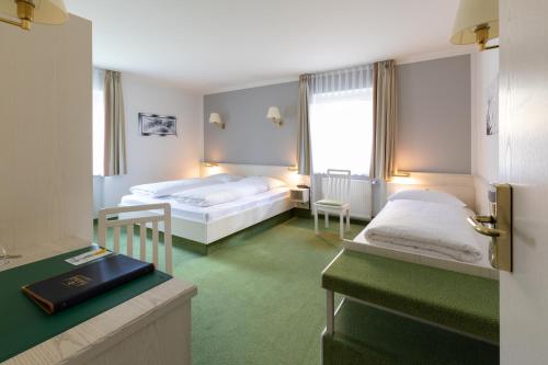 a hotel room with two beds and a desk at Landhotel Huberhof Allershausen in Allershausen