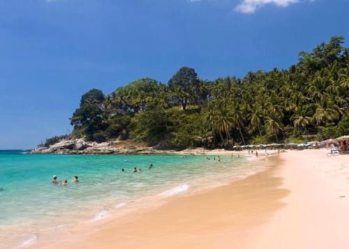 a group of people swimming in the water on a beach at Surin Bay Inn in Surin Beach