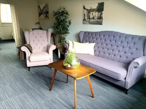 a living room with a purple couch and two chairs at Het Begijnhof Tongeren Center in Tongeren