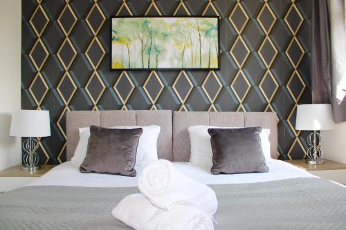 a bedroom with two beds with pillows and a painting at Homely and Budget Friendly 3 bed house Sleeps 6 Free Parking! in Milton Keynes