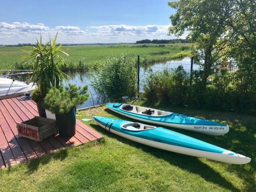 tres kayaks sentados en una cubierta junto a un cuerpo de agua en Baltic Waterfront Yacht House - PRIVATE Garden & Watersports Included, en Świnoujście