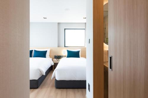 a hotel room with two beds with blue pillows at Connect Busan Hotel & Residence in Busan
