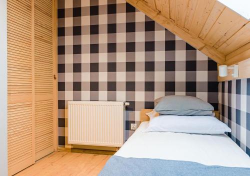 a bed in a room with a checkered wall at Apartamenty-Obok 1 in Zator
