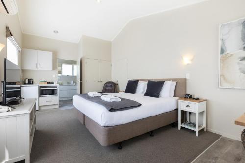 a bedroom with a large bed and a kitchen at Colonial Court Motor Inn in Tauranga