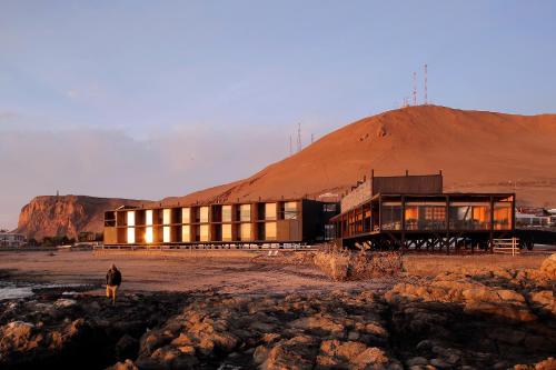 a person standing in front of a building in the desert at Hotel Apacheta in Arica