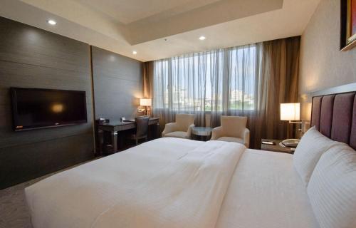 a hotel room with a large bed and a television at Arsma Hotel in Hualien City