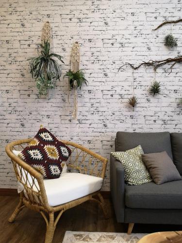 a wicker chair and a couch in front of a brick wall at Dsara Suite Near Hospital Sungai Buloh by ADDS in Sungai Buluh