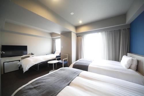 a hotel room with two beds and a television at Dormy Inn Miyazaki Natural Hot Spring in Miyazaki