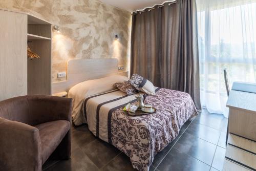 une chambre d'hôtel avec un lit et une chaise dans l'établissement Hôtel Morris, à Le Pont-de-Beauvoisin