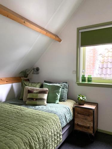 a bedroom with a green bed and a window at Apartment In de Wolken in Oostwoud