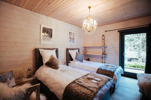 a bedroom with two beds and a chandelier at Chalet à l'aise met Wellness, Durbuy in Durbuy