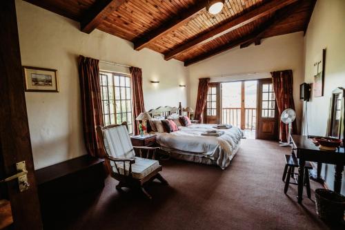 a bedroom with a bed and a chair in a room at Ndawana River Lodge in Underberg