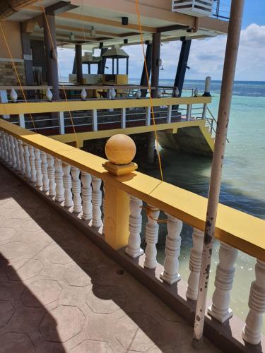 a yellow railing on a pier next to the water at L & M Hearthstones Lodge in Oslob