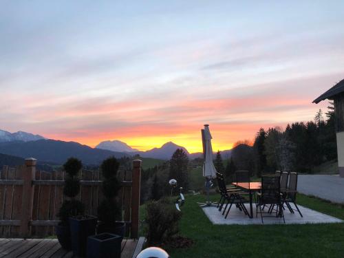 een patio met een tafel en stoelen en een zonsondergang bij Möselberghof in Abtenau